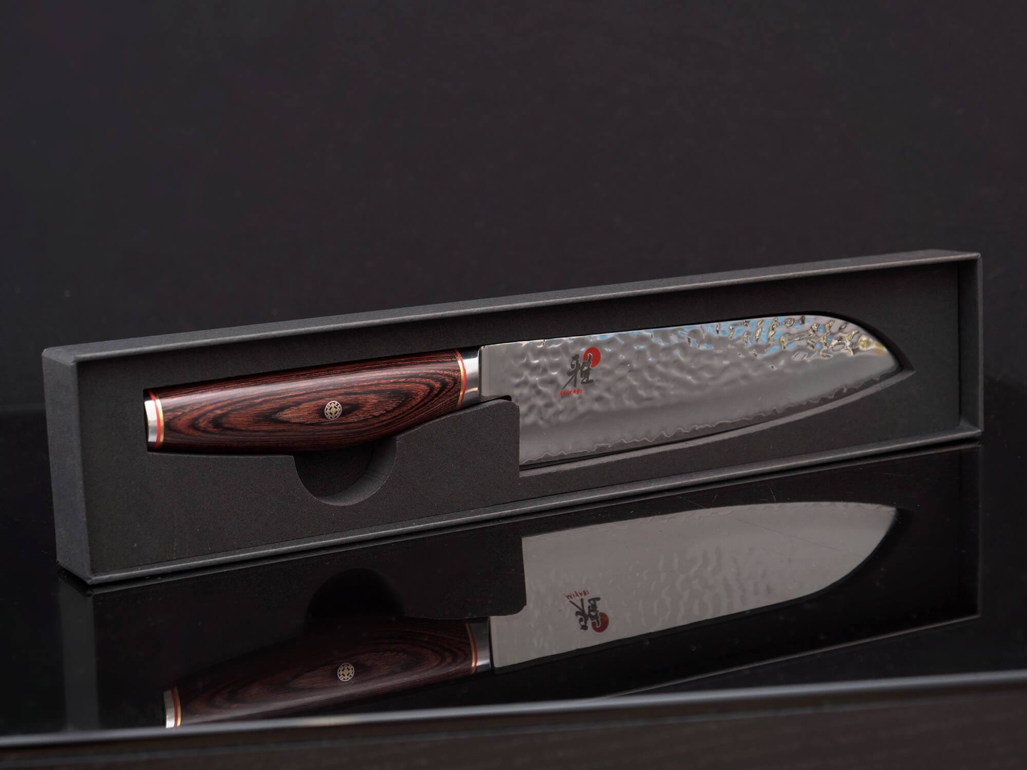 Ein Santokumesser von Miyabi. Die Klinge ist gehämmert und hochglanzpoliert. Der Griff ist leicht bauchig aus braunem Pakkaholz.